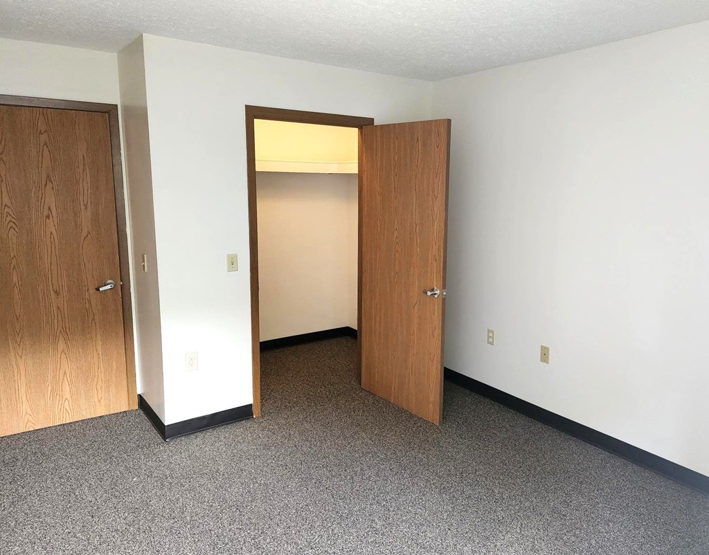 an empty room with two doors and a closet