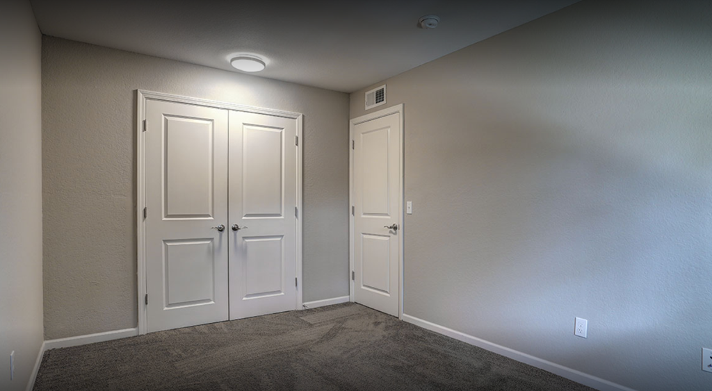 a empty room with two doors and a carpeted floor