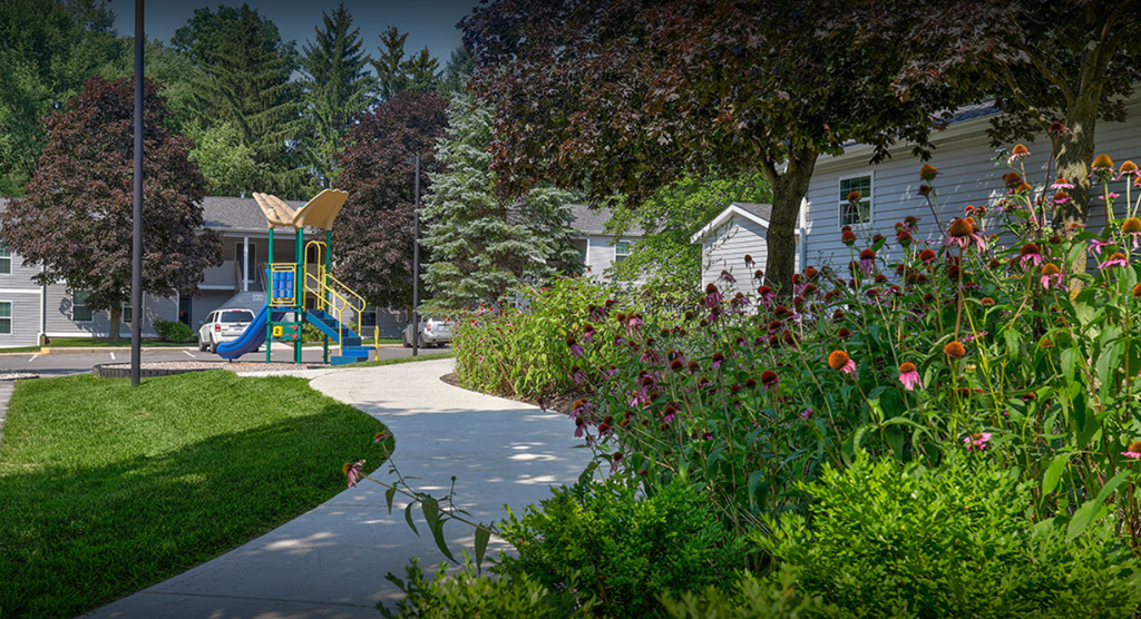 a sidewalk leading to a playground in front of a house