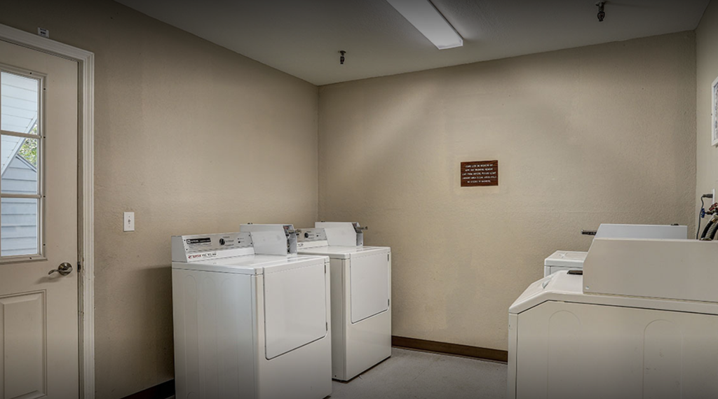 a laundry room with four washers and dryers and a door to a door