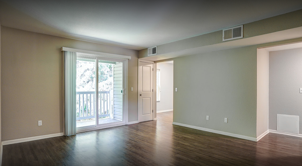 an empty living room with a door to a balcony