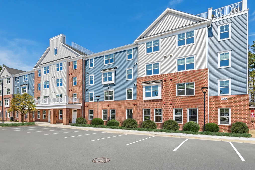 a brick apartment building with blue siding and a parking lot