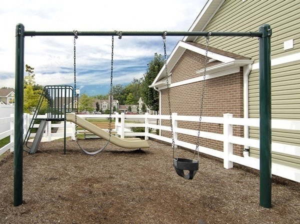 a swing set in a backyard with a white fence