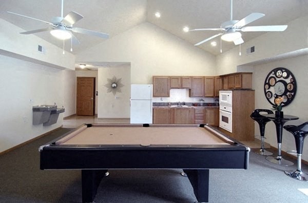 a living room with a pool table and a kitchen