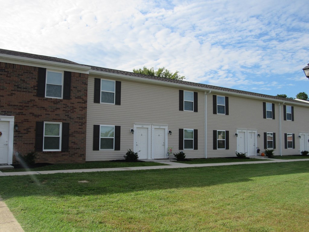a large apartment building with white doors and a lawn