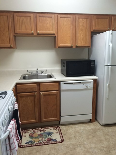 A kitchen with a white refrigerator, a black microwave, a white dishwasher, and a white stove.