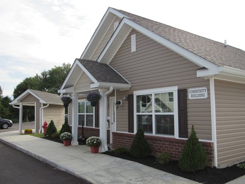 the front entrance of a tan house with a sidewalk and potted plants