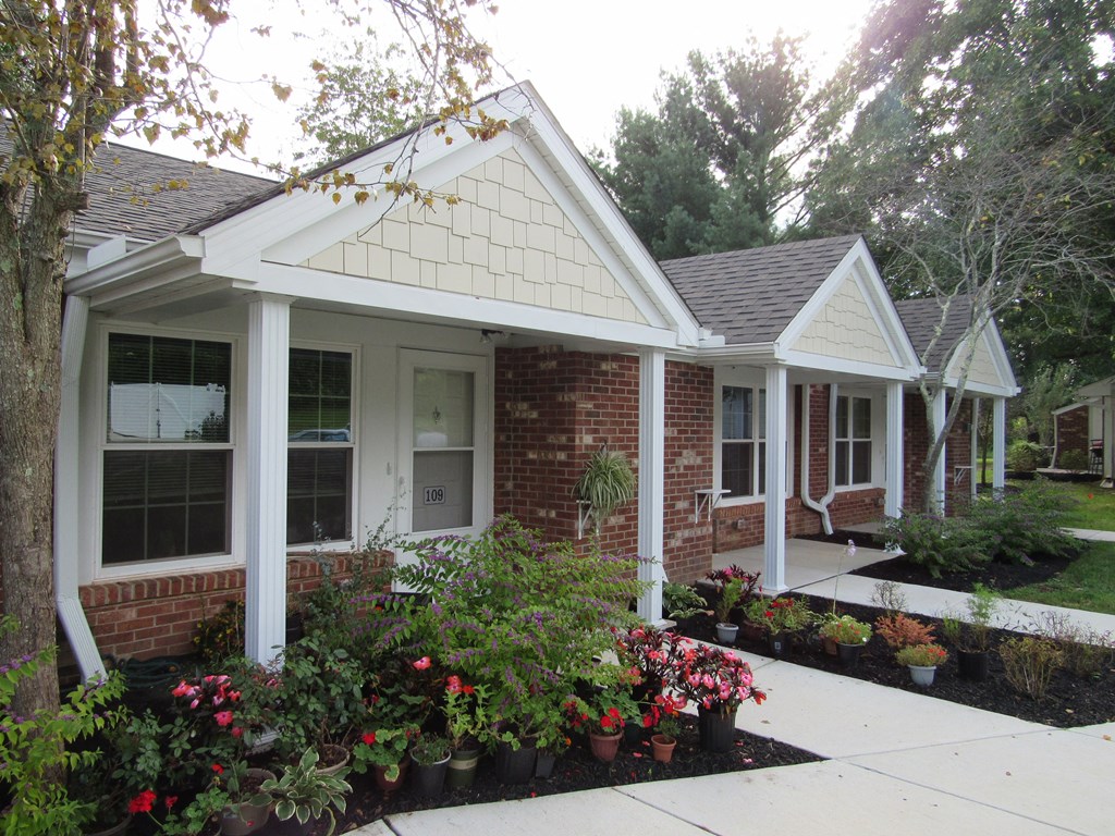 a front porch with flowers in front of a brick house