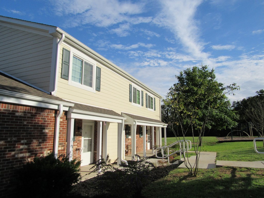 a view of the side of a house with a porch and a tree