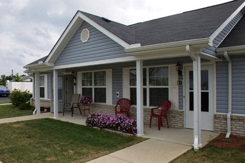 a blue house with rocking chairs on a porch