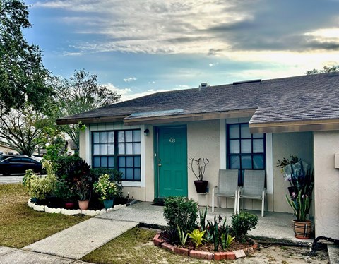 A house with a green door and a white chair in front of it.