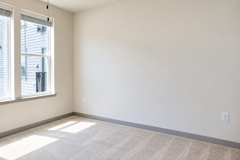 A room with a carpeted floor and a window with blinds.