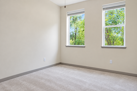 A room with two windows showing trees outside.