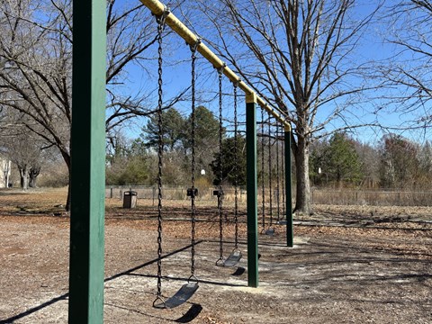 A playground swing set with a yellow bar and two swings.