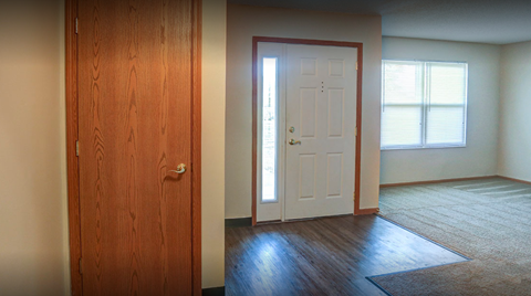 an empty living room with a white door and wood floors