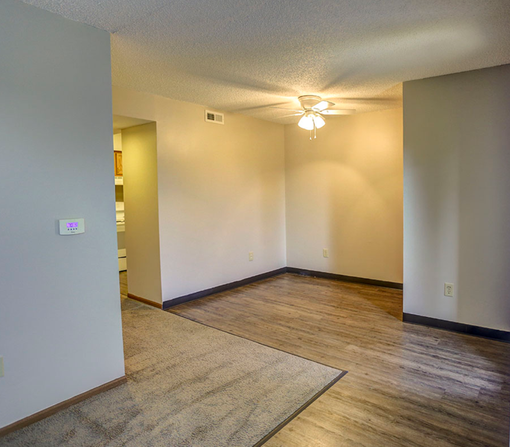 the living room and dining room of an empty house with a ceiling fan