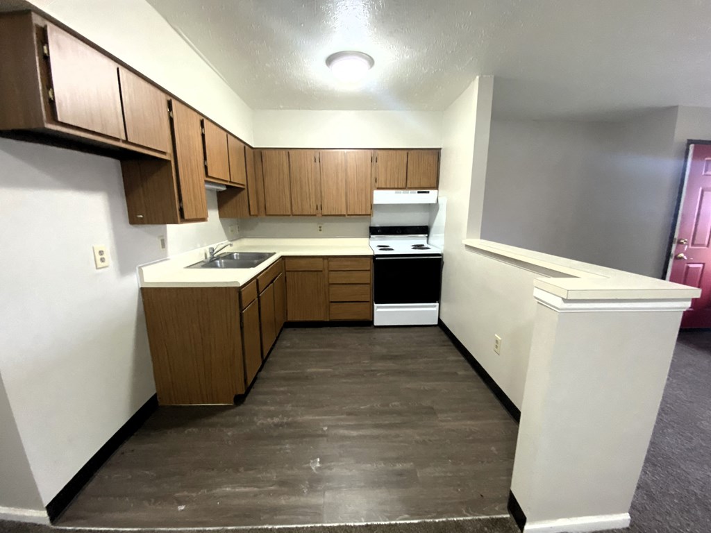 an empty kitchen with wooden cabinets and white walls