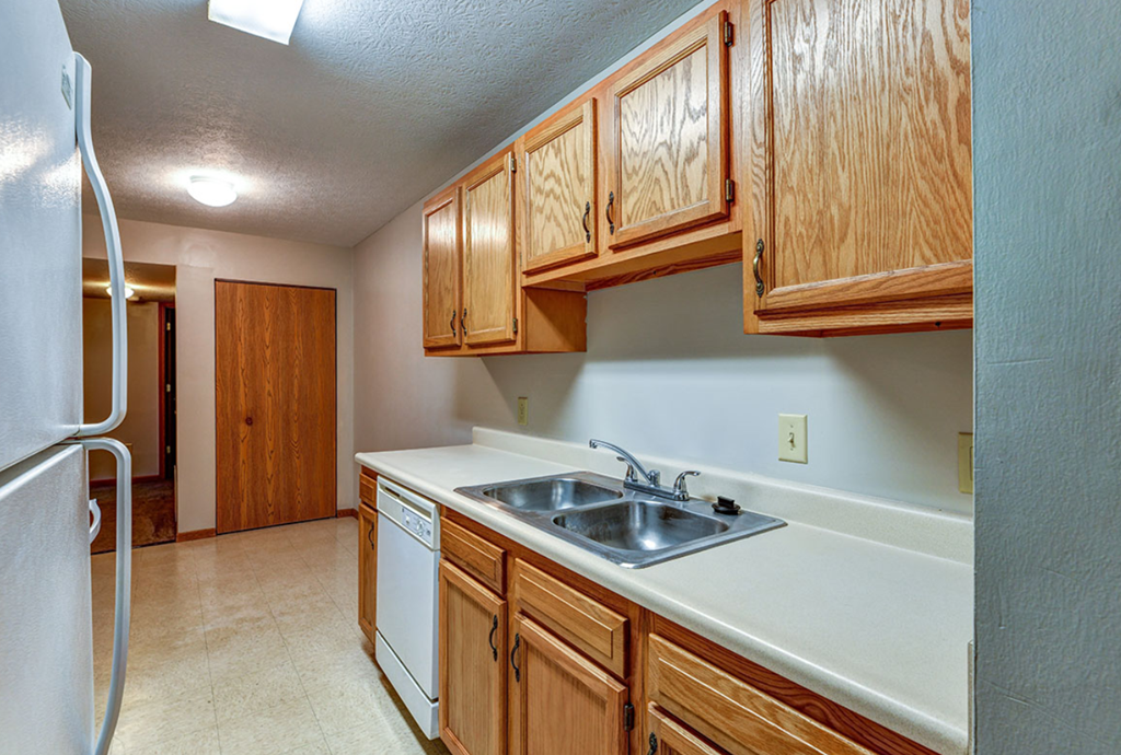 a kitchen with a sink and cabinets and a refrigerator