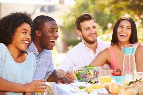a group of people sitting at a table with food and drinks