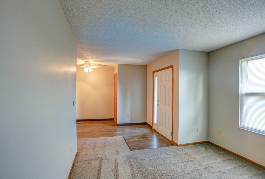 an empty living room with a white door and a window