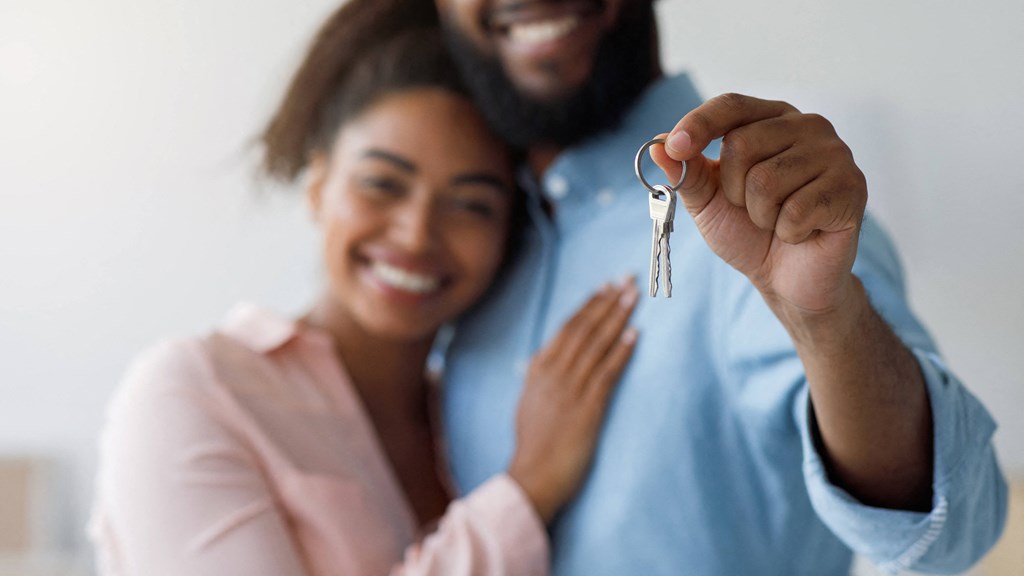 a man and woman holding a key to a house