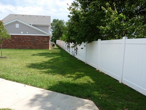 a white fence in a yard in front of a house