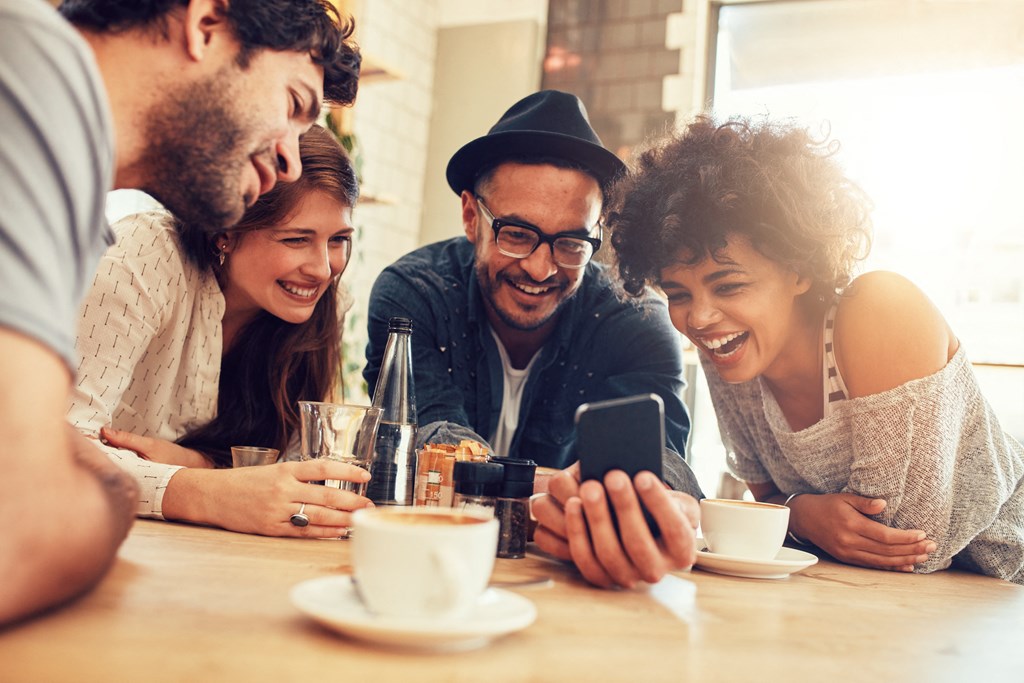 a group of people sitting at a table looking at a cell phone