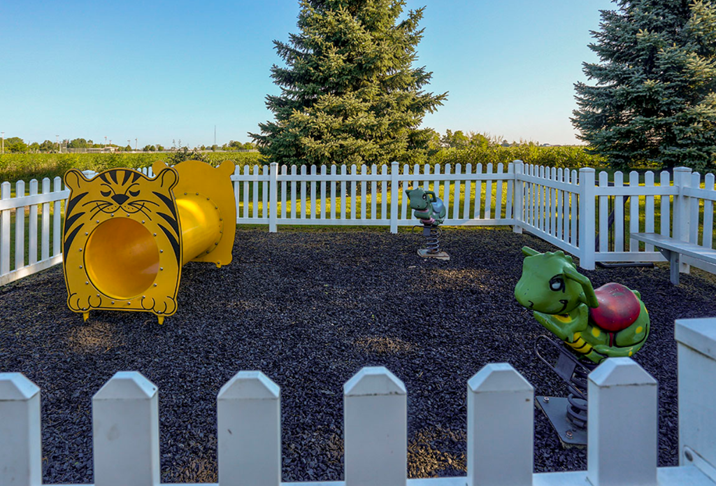 children s playgrounds in a park with a white fence