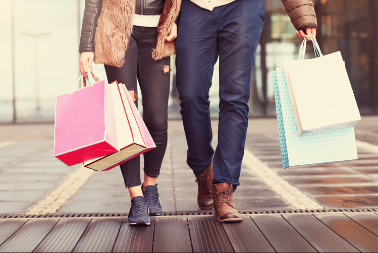 three people walking down the street with shopping bags