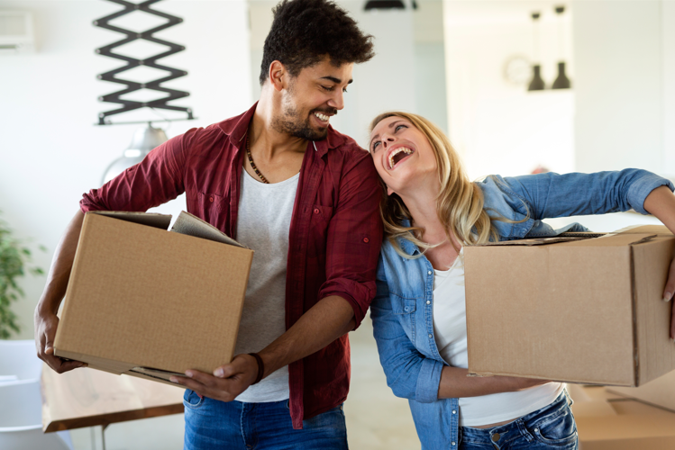 a man and a woman laughing while holding boxes