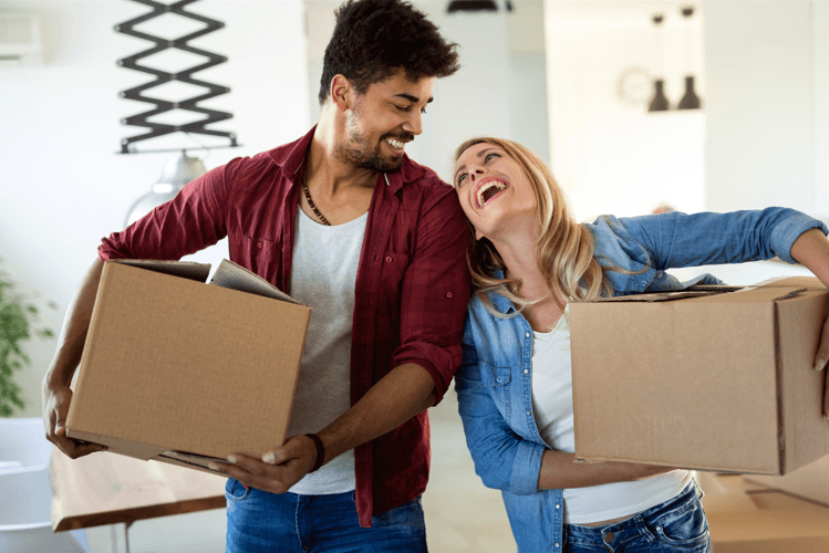 a man and a woman laughing while holding cardboard boxes