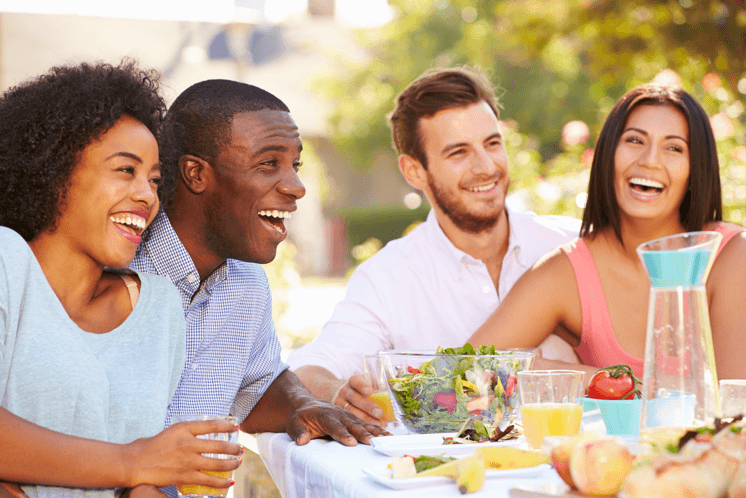 a group of people sitting at a table with food and drinks