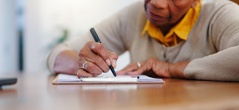 A person is writing in a notebook with a pen.