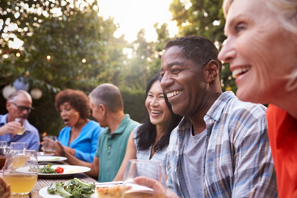 a group of people sitting around a table talking and eating food