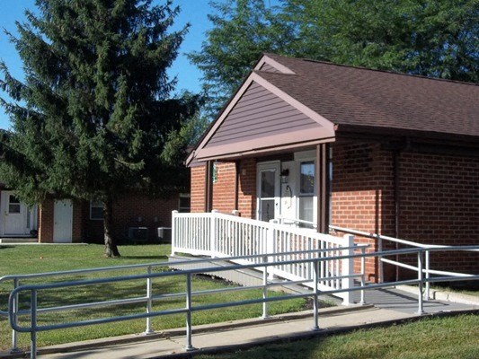 a small red brick building with a white porch