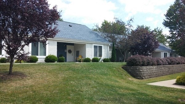 a white house with a lawn and a brick retaining wall