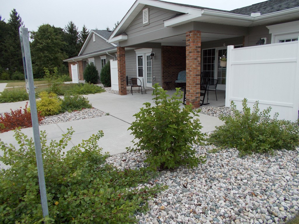 a yard with gravel and bushes in front of a house