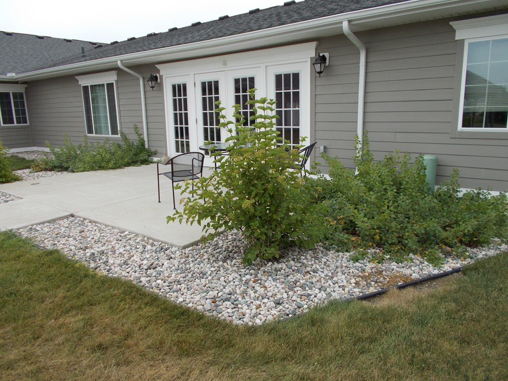 a patio with plants and chairs in front of a house