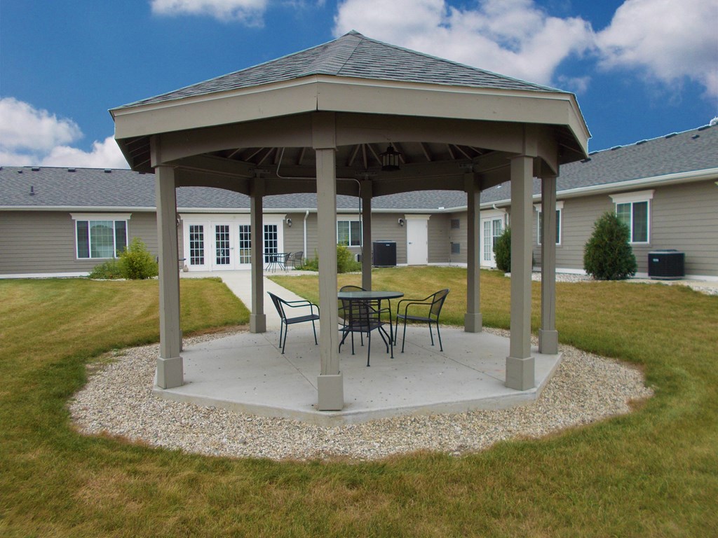 a gazebo with a table and chairs on a concrete patio