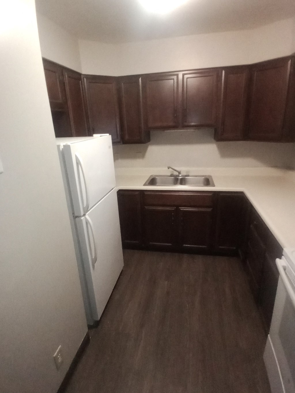 an empty kitchen with a refrigerator and a sink