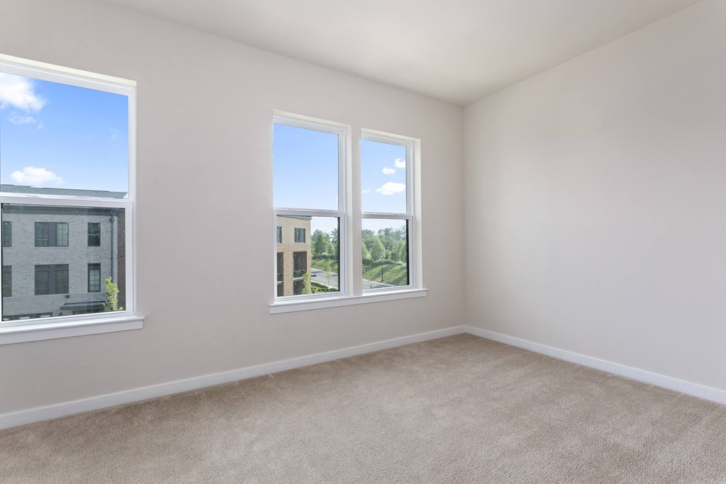 a bedroom with three windows and a carpeted floor