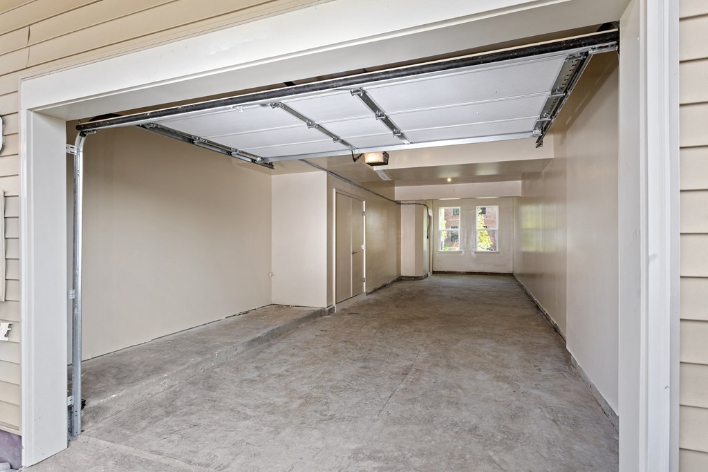 an empty corridor in a building with a garage door open
