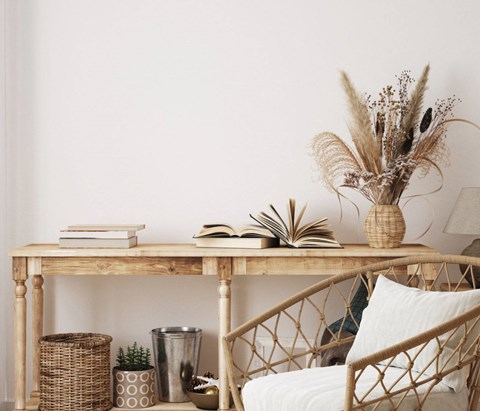 A table with a vase of dried flowers, a stack of books, and a plant on it.