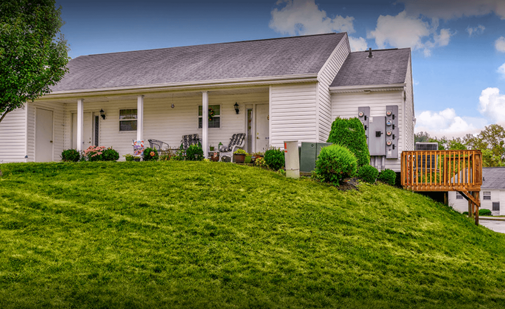 a white house with a porch on a hill