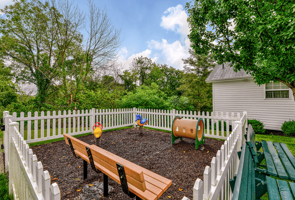 a fenced in backyard with a garden and benches