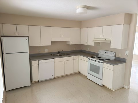 A kitchen with white appliances and cabinets.