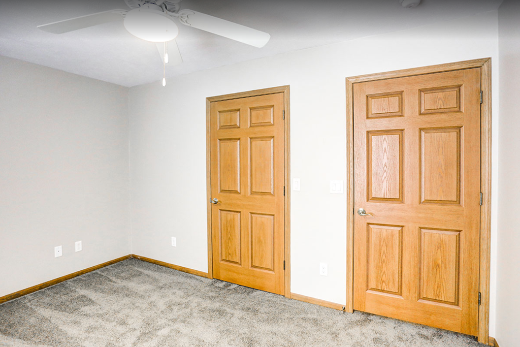 an empty room with two wooden doors and a carpet