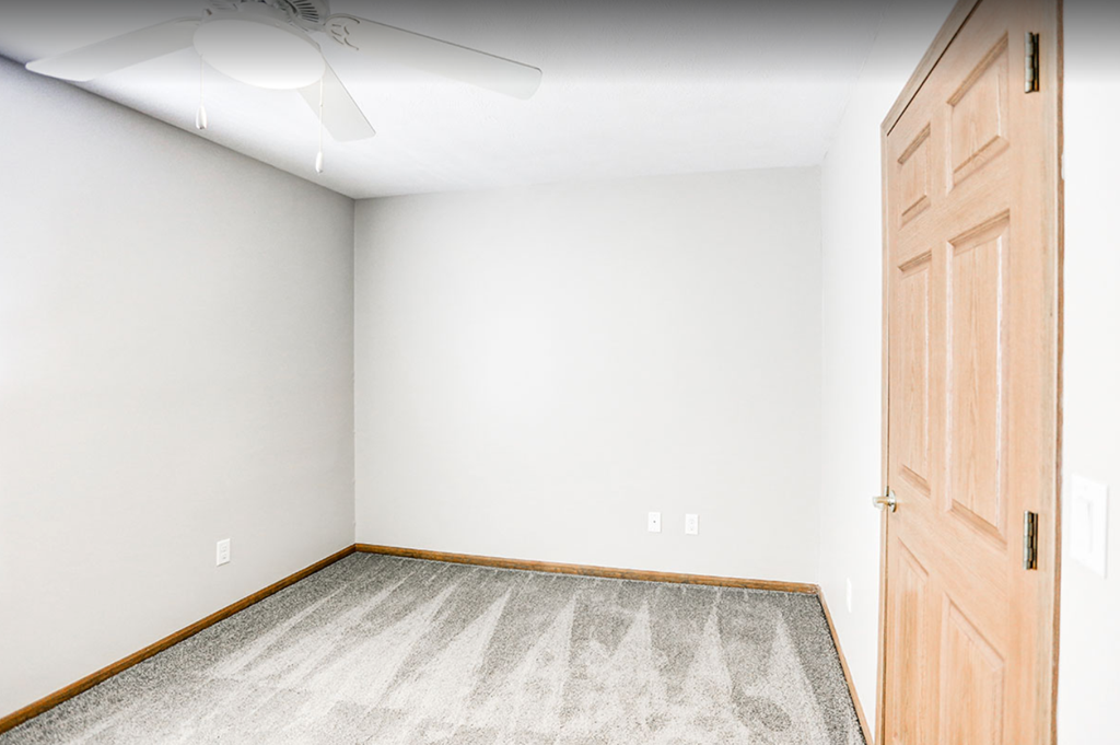 an empty room with a wooden door and carpet