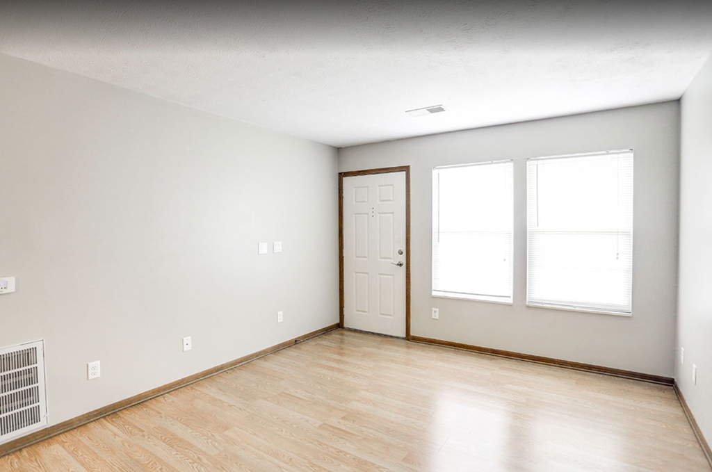 an empty room with a door and two windows