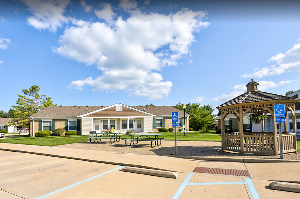 a gazebo and picnic tables in a park in front of a house